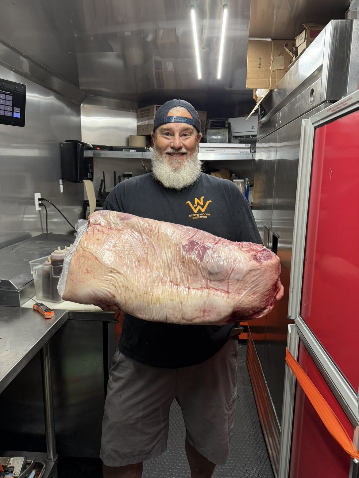 Sean smiling while holding a whole brisket inside the food trailer