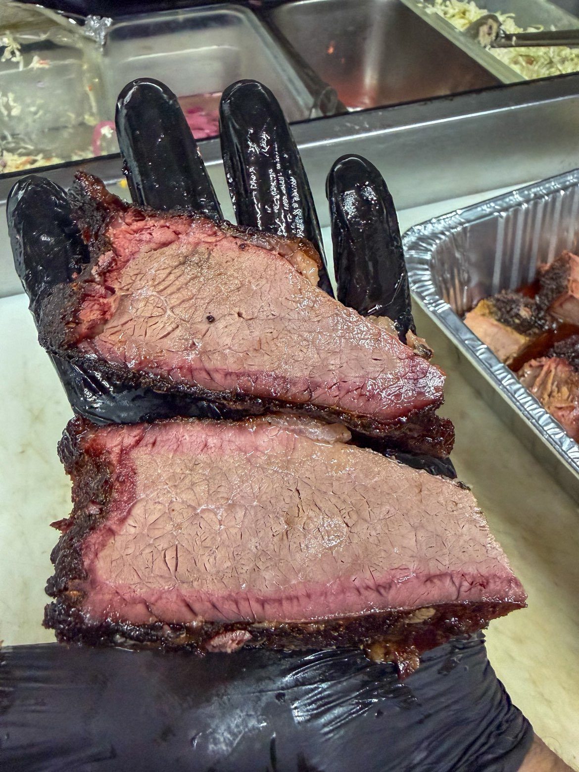 Two thick slices of smoked brisket showing a dark bark and smoke ring
